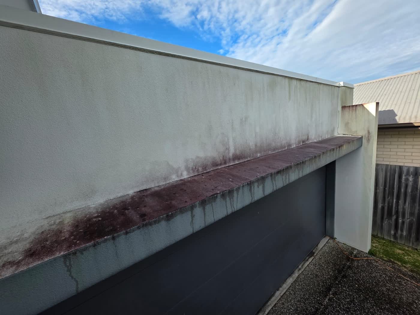Rendered house wall soft washed to remove mould and red algae staining — before