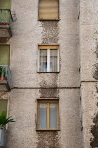 Detailed view of a vintage residential building's facade with balconies and windows, showcasing urban architecture.